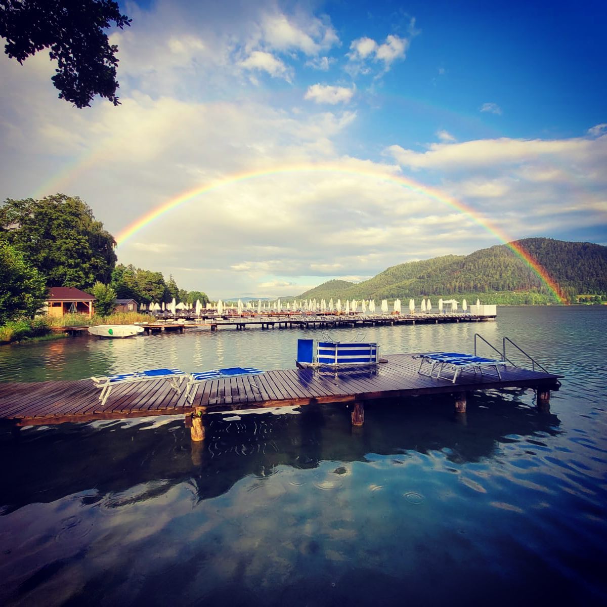 Foto des Klopeiner See mit Regenbogen im Hintergrund.